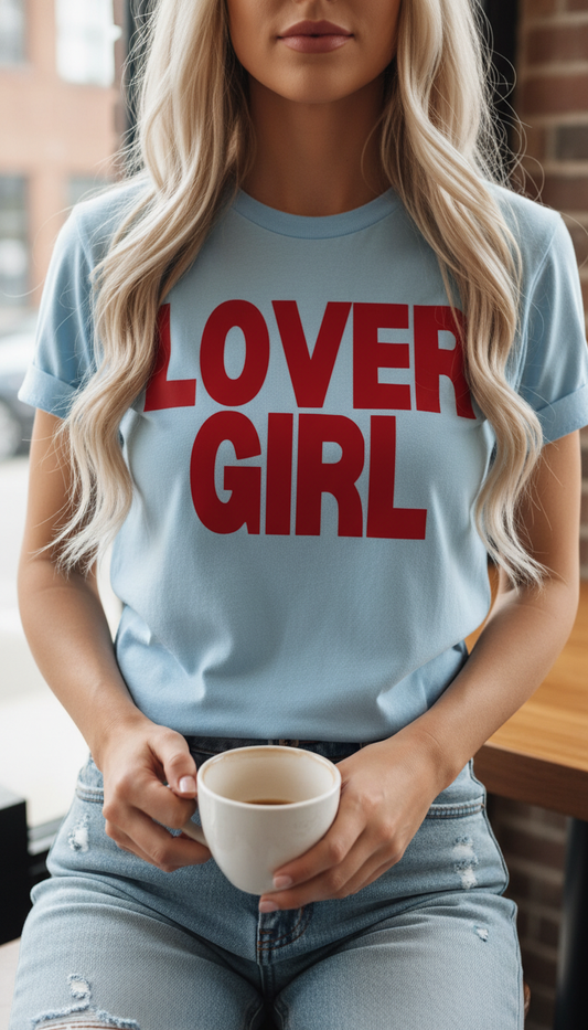 Woman wearing a light blue t-shirt with 'LOVER GIRL' in red text, holding a cup.