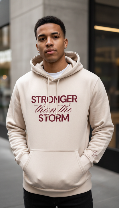 Man wearing a beige hoodie with 'Stronger than the storm' text in red.
